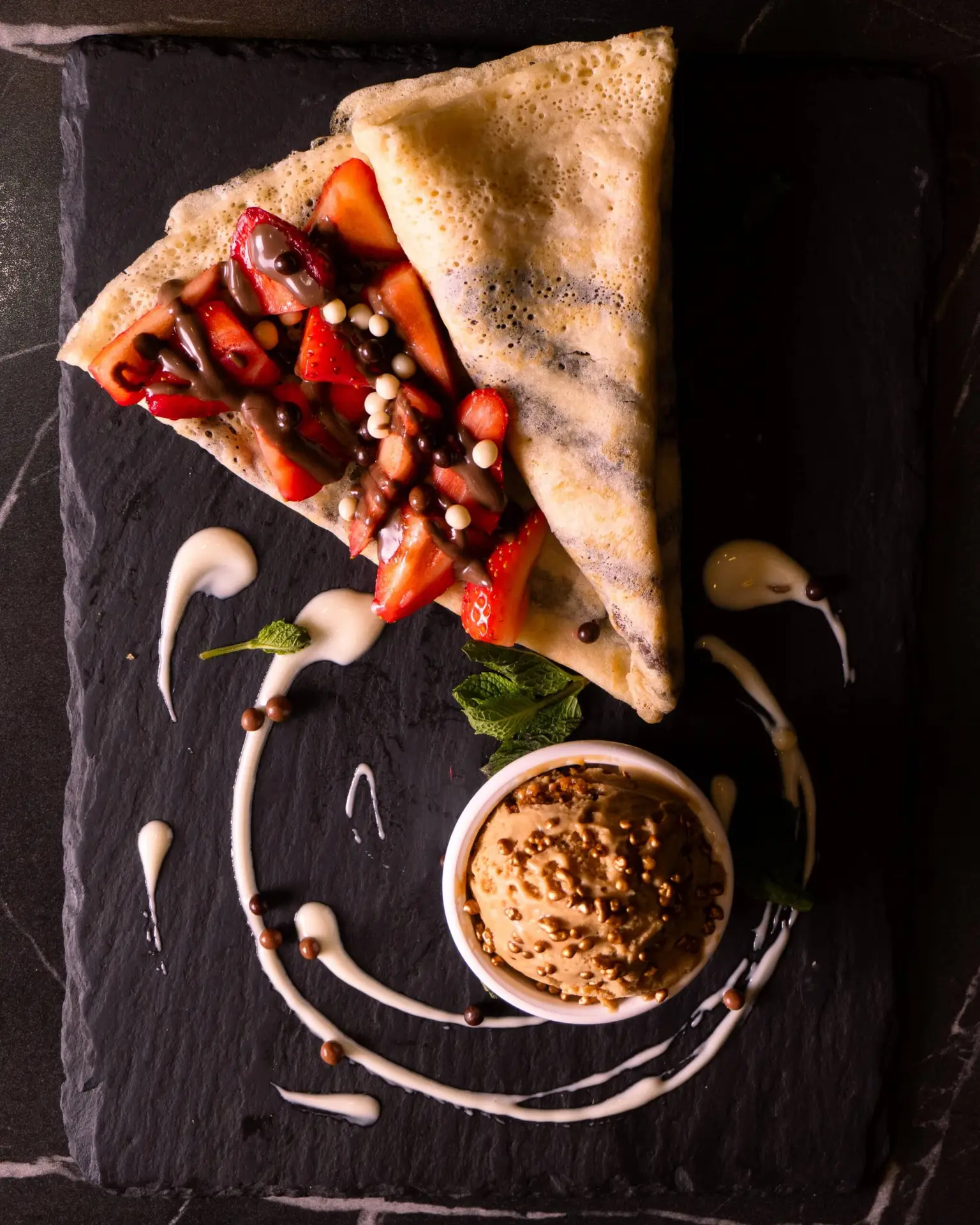 Crepe with strawberries and ice cream on slate